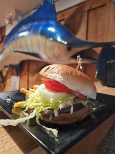 Smashburger with lettuce, tomato, and onion served with crinkle fries on a black plate at Captain Eddie's Seafood in Nokomis, FL